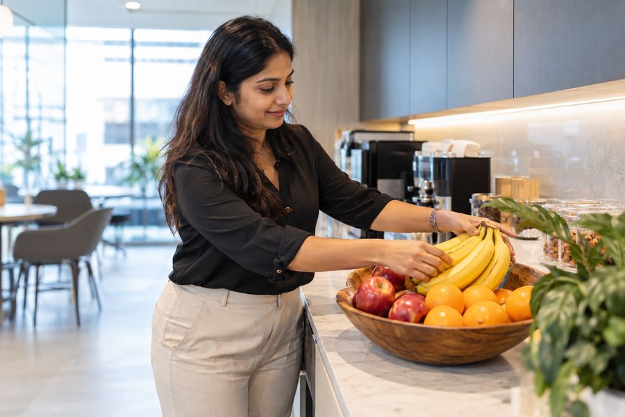 An office worker restocking a fruit basket in a corporate pantry